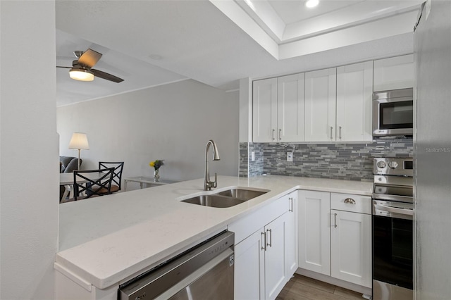 kitchen with white cabinets, sink, decorative backsplash, kitchen peninsula, and stainless steel appliances