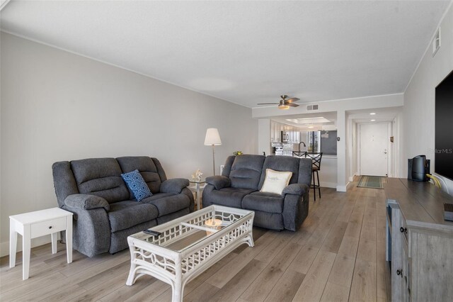 living room with light hardwood / wood-style flooring and ceiling fan