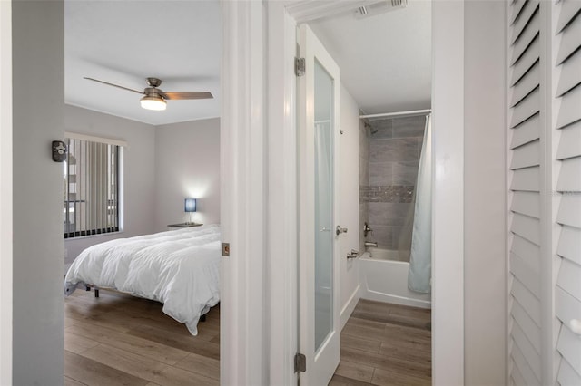 bedroom with connected bathroom, ceiling fan, and wood-type flooring