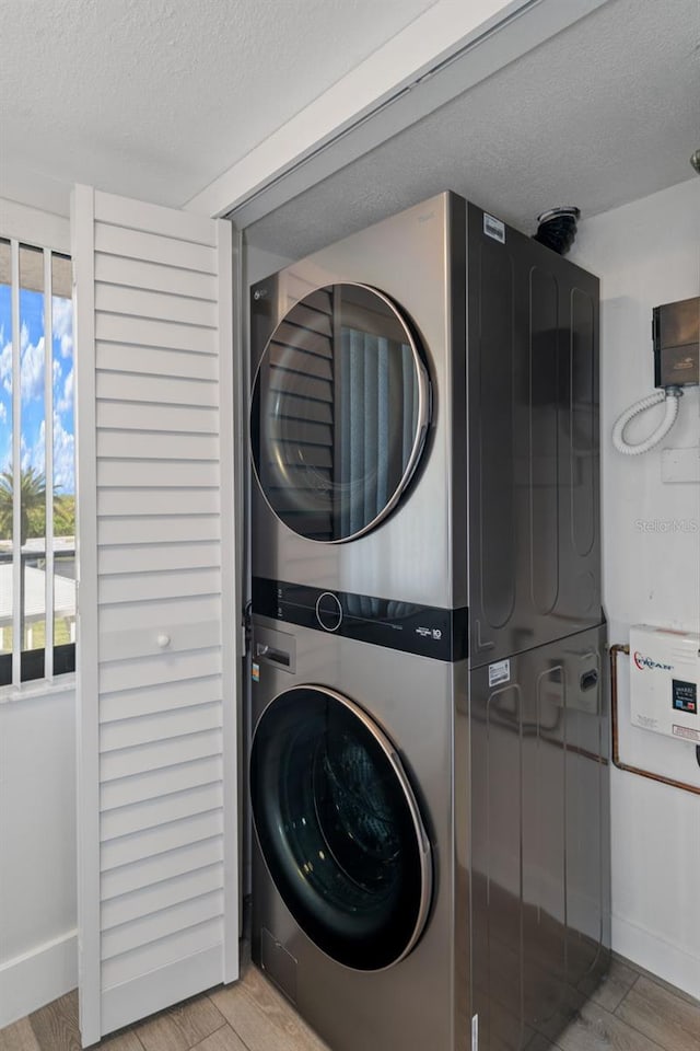 washroom featuring light hardwood / wood-style floors, a textured ceiling, and stacked washer and clothes dryer