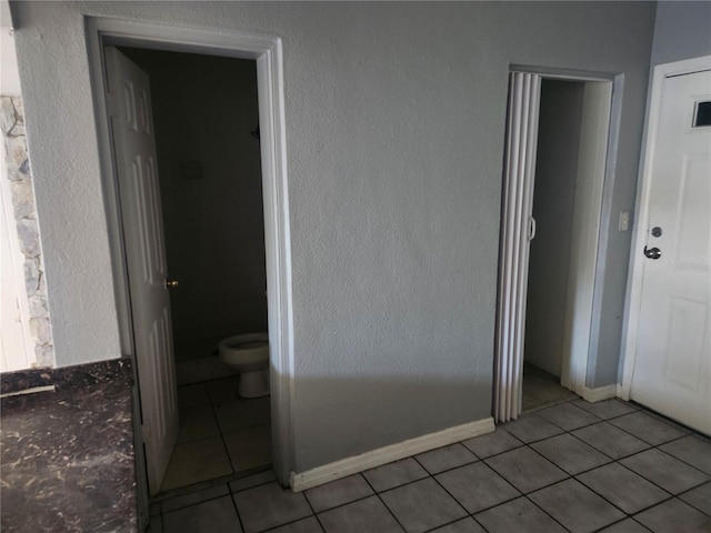 interior space with light tile patterned floors, connected bathroom, and a closet