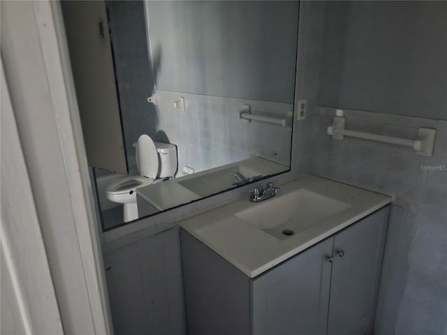 bathroom featuring vanity, tile walls, and toilet