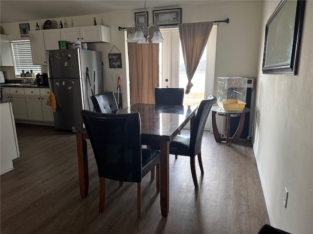 dining area with dark hardwood / wood-style flooring and an inviting chandelier