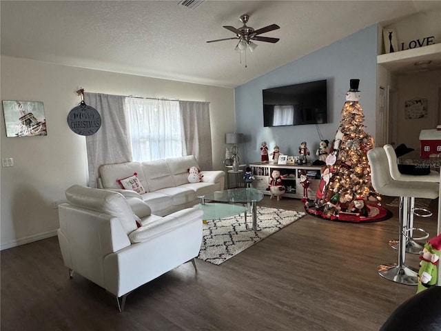 living room with a textured ceiling, vaulted ceiling, ceiling fan, and dark wood-type flooring