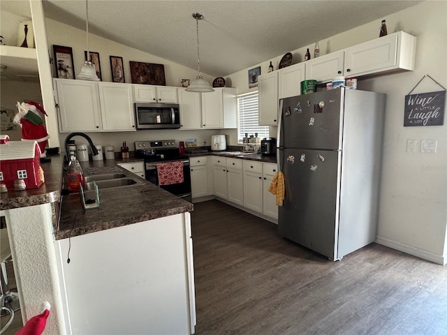 kitchen featuring sink, hanging light fixtures, vaulted ceiling, appliances with stainless steel finishes, and white cabinetry