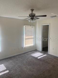 unfurnished room with dark colored carpet and ceiling fan