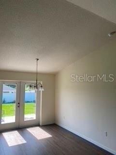 unfurnished room featuring a textured ceiling, french doors, dark wood-type flooring, and an inviting chandelier