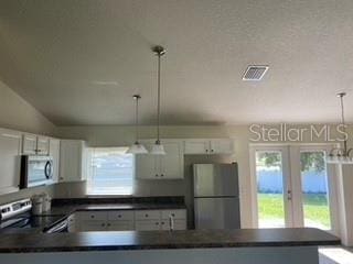 kitchen featuring appliances with stainless steel finishes, decorative light fixtures, white cabinetry, and french doors