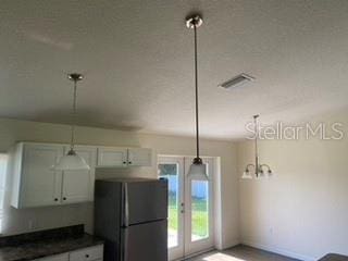 kitchen featuring white cabinets, pendant lighting, and fridge