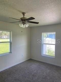 unfurnished room featuring ceiling fan, dark carpet, and a textured ceiling