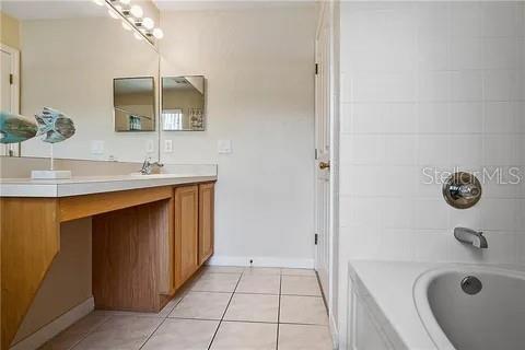 bathroom with tile patterned floors, vanity, and tiled shower / bath