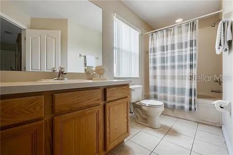 full bathroom with tile patterned flooring, vanity, toilet, and shower / bathtub combination with curtain