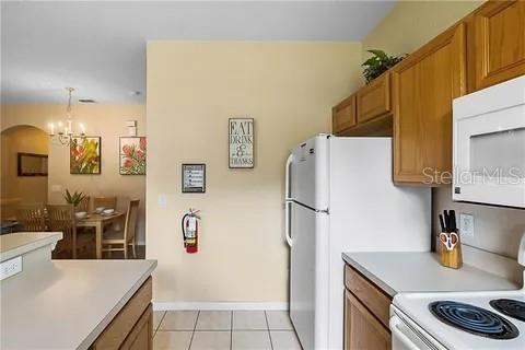 kitchen featuring light tile patterned floors, pendant lighting, white appliances, and an inviting chandelier