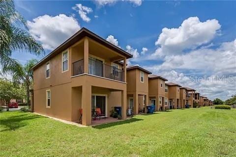 rear view of property with a lawn and a balcony