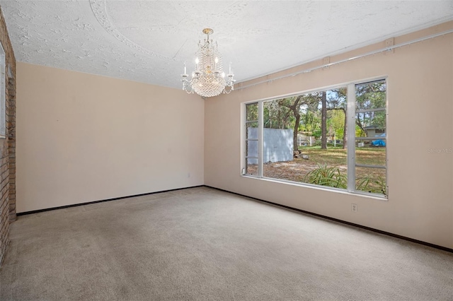 spare room with carpet flooring, a chandelier, and a textured ceiling