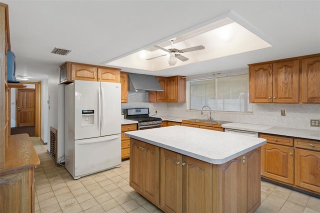 kitchen featuring sink, wall chimney exhaust hood, stainless steel gas stove, white fridge with ice dispenser, and a kitchen island