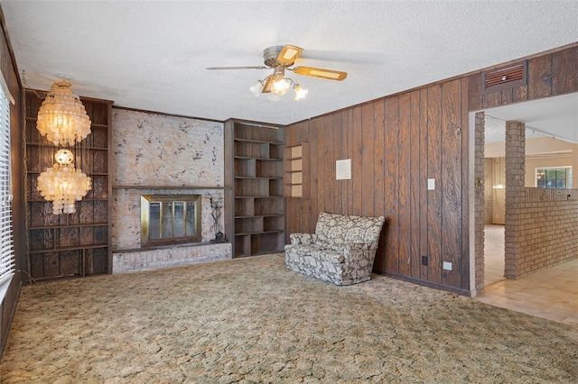 interior space with wooden walls, carpet floors, ceiling fan with notable chandelier, and a textured ceiling