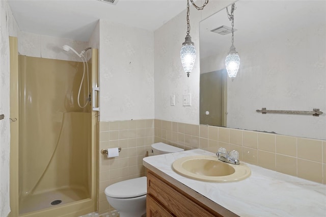 bathroom featuring a shower, vanity, toilet, and tile walls