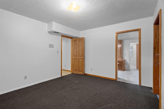 unfurnished bedroom with dark carpet and a textured ceiling