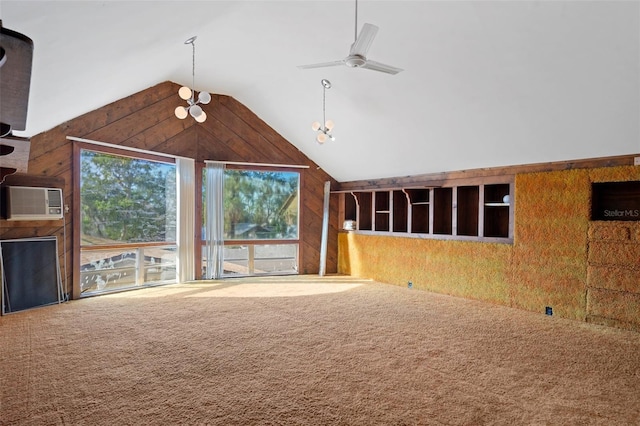 unfurnished living room with ceiling fan, high vaulted ceiling, a wall mounted AC, wooden walls, and carpet