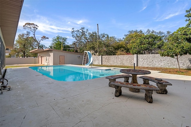 view of swimming pool with a patio area, an outdoor structure, and a water slide