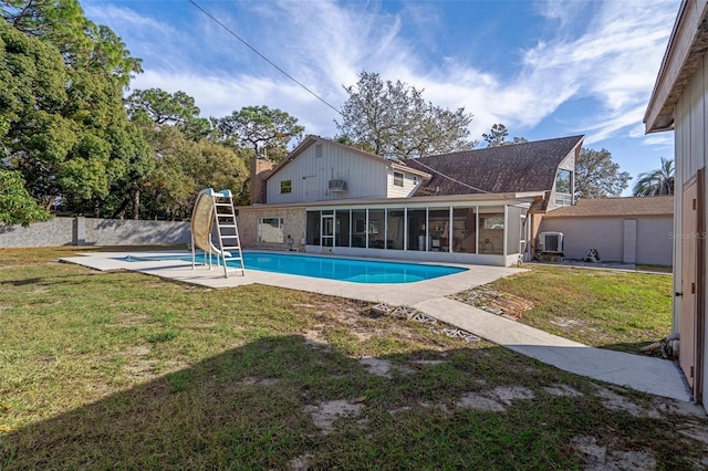 view of pool with a sunroom, a water slide, and a lawn