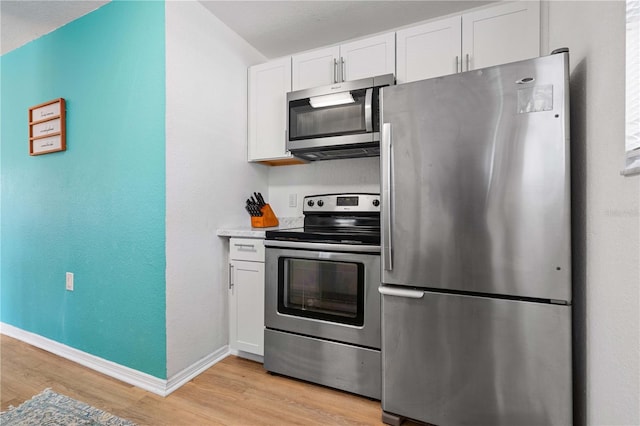 kitchen with appliances with stainless steel finishes, light wood-type flooring, and white cabinetry