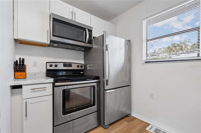 kitchen featuring white cabinets, light hardwood / wood-style floors, and appliances with stainless steel finishes