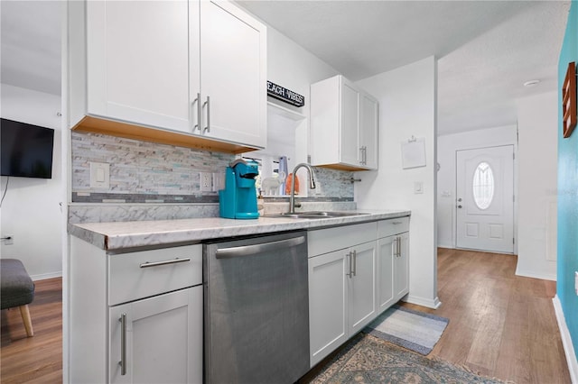 kitchen with sink, tasteful backsplash, dark hardwood / wood-style flooring, stainless steel dishwasher, and white cabinets