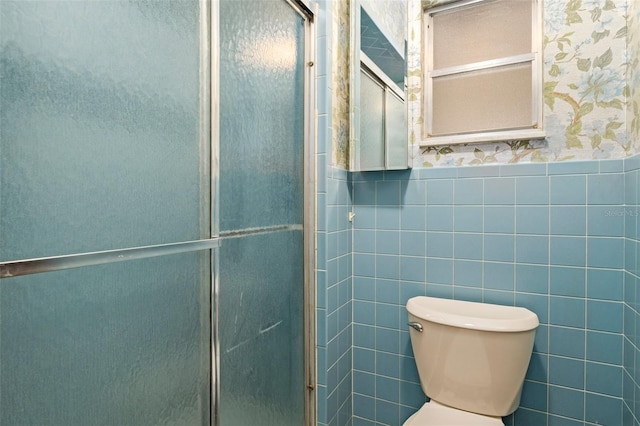 bathroom with an enclosed shower, toilet, and tile walls