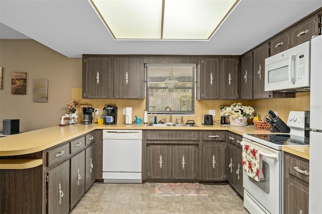 kitchen with kitchen peninsula, tasteful backsplash, white appliances, dark brown cabinetry, and sink