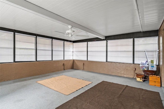 unfurnished sunroom featuring beam ceiling, ceiling fan, and plenty of natural light