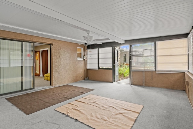 unfurnished sunroom featuring beam ceiling and ceiling fan