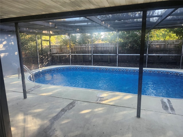 view of pool with glass enclosure and a patio