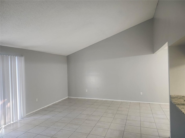 empty room featuring light tile patterned floors, a textured ceiling, and lofted ceiling