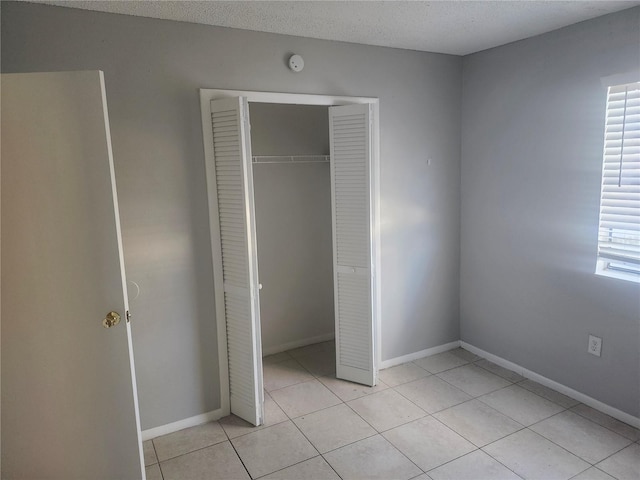 unfurnished bedroom featuring light tile patterned floors, a textured ceiling, and a closet