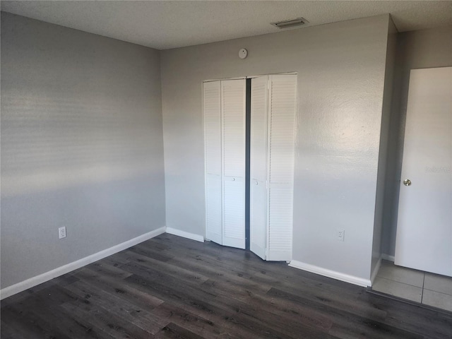 unfurnished bedroom with dark hardwood / wood-style floors and a closet