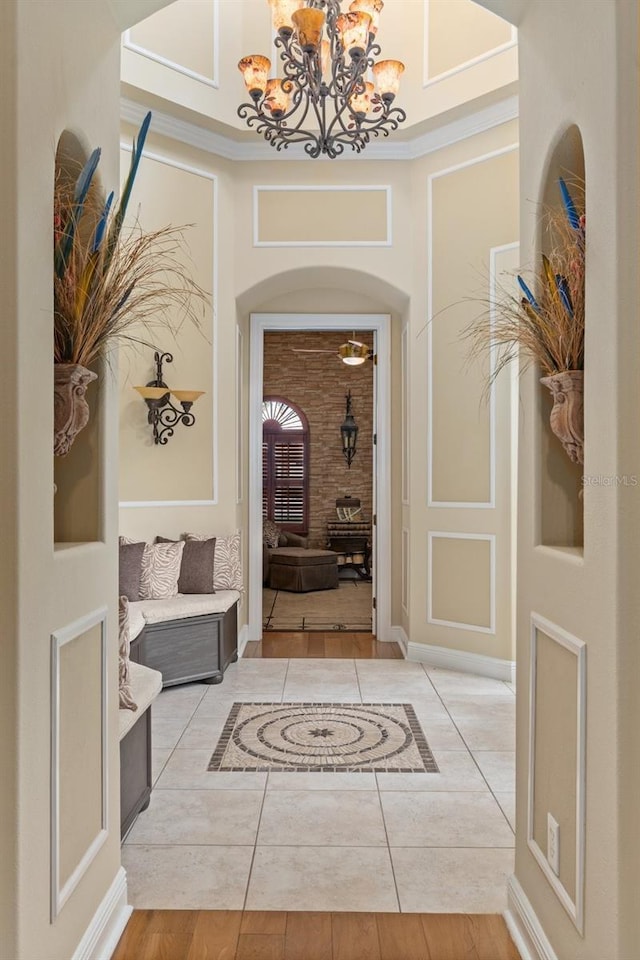 foyer entrance featuring a chandelier, light tile patterned floors, and crown molding