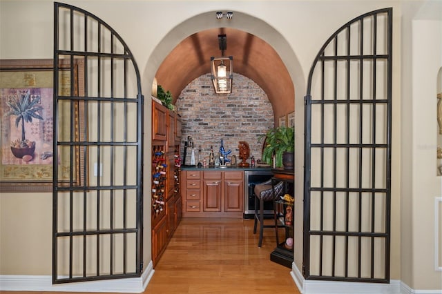 wine cellar with bar area, beverage cooler, vaulted ceiling, and light hardwood / wood-style floors