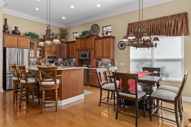 kitchen with stainless steel appliances, light hardwood / wood-style flooring, a notable chandelier, an island with sink, and pendant lighting