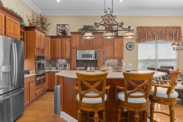 kitchen with crown molding, hanging light fixtures, decorative backsplash, appliances with stainless steel finishes, and light hardwood / wood-style floors