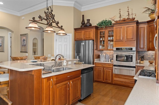 kitchen with sink, decorative light fixtures, a breakfast bar area, appliances with stainless steel finishes, and light wood-type flooring