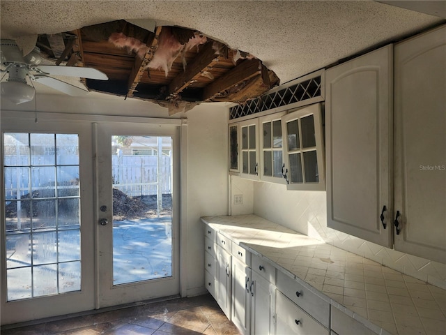 interior space with white cabinets, ceiling fan, tile patterned floors, and french doors