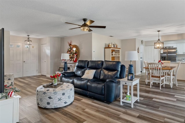 living room with wood-type flooring, a textured ceiling, and ceiling fan