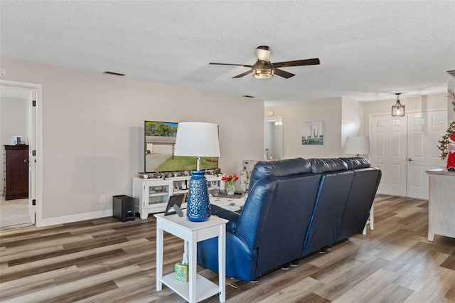 living room featuring hardwood / wood-style floors, ceiling fan, and a textured ceiling