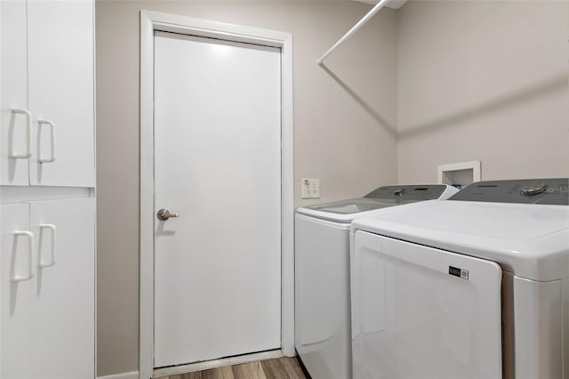 clothes washing area with washer and dryer and light hardwood / wood-style floors