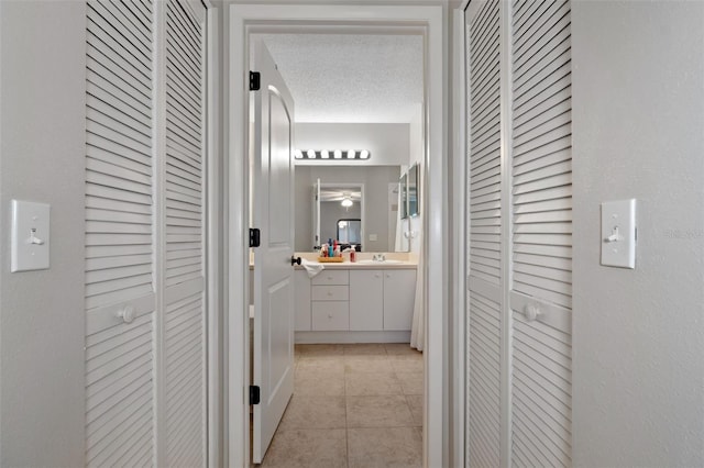 hallway featuring light tile patterned flooring, a textured ceiling, and sink