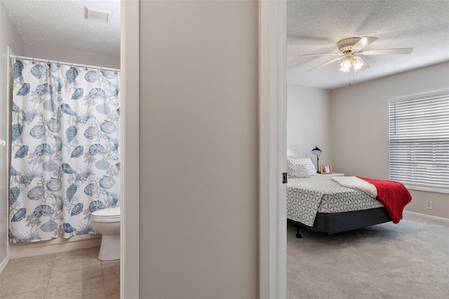 carpeted bedroom with ceiling fan and a textured ceiling