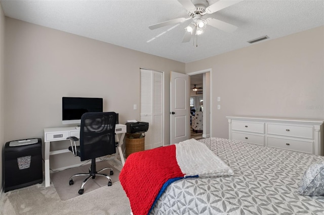 carpeted bedroom with ceiling fan, a closet, and a textured ceiling