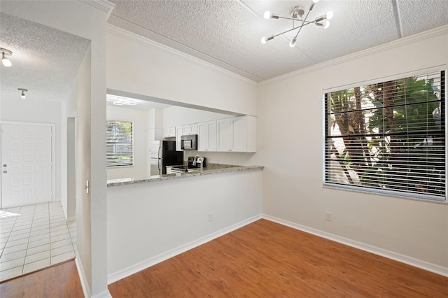 kitchen with white cabinetry, light stone counters, a notable chandelier, appliances with stainless steel finishes, and light wood-type flooring